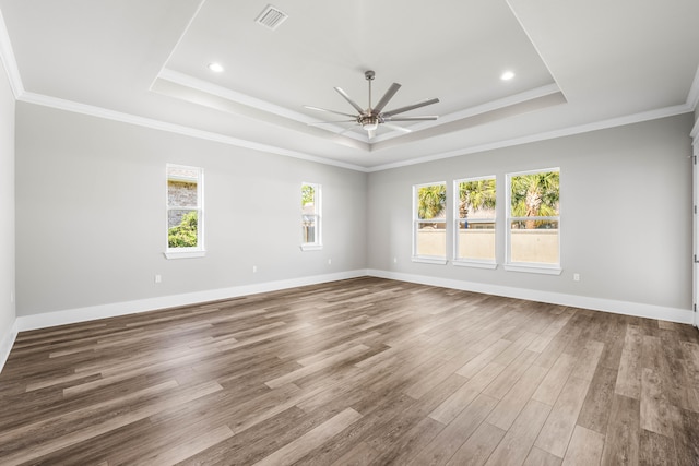 empty room with ceiling fan, hardwood / wood-style flooring, a raised ceiling, and crown molding