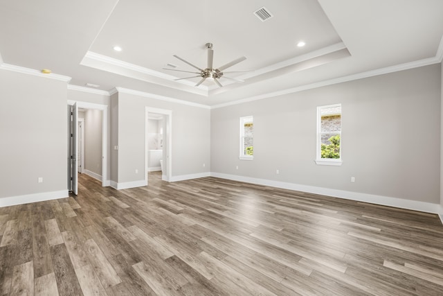 empty room with ornamental molding, ceiling fan, a tray ceiling, and wood-type flooring