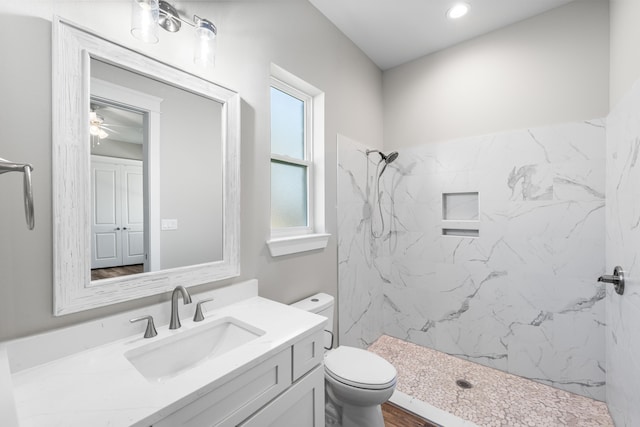 bathroom featuring a tile shower, vanity, toilet, and wood-type flooring