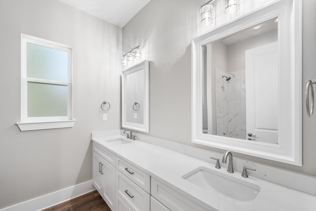 bathroom featuring a tile shower, vanity, and wood-type flooring