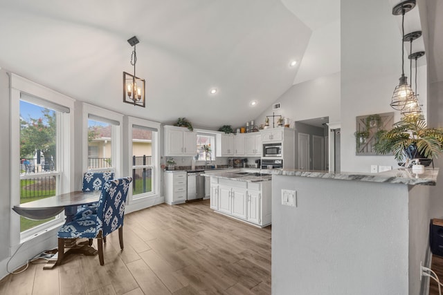 kitchen featuring decorative light fixtures, high vaulted ceiling, light hardwood / wood-style flooring, and white cabinets