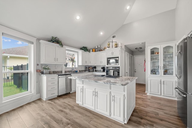 kitchen with a wealth of natural light, a kitchen island, white cabinetry, and stainless steel appliances