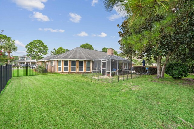 rear view of house featuring glass enclosure and a lawn