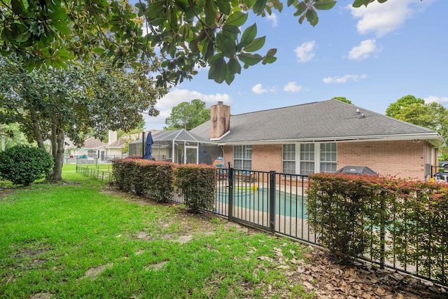 rear view of property with glass enclosure, a lawn, and a fenced in pool