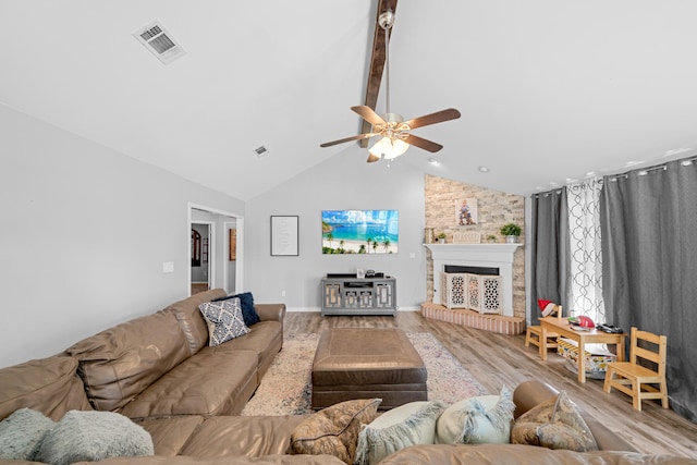 living room with a large fireplace, high vaulted ceiling, beamed ceiling, light hardwood / wood-style floors, and ceiling fan