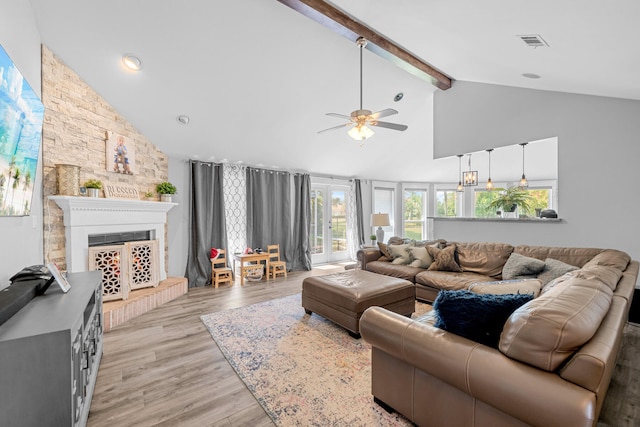 living room featuring ceiling fan, light wood-type flooring, high vaulted ceiling, beam ceiling, and a fireplace