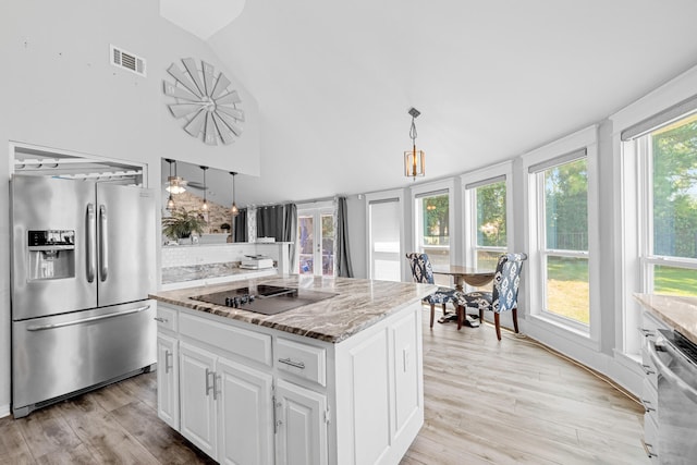 kitchen with white cabinets, hanging light fixtures, appliances with stainless steel finishes, and light hardwood / wood-style floors