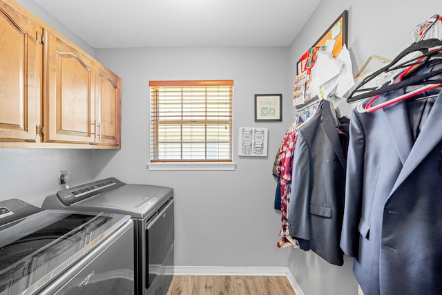 clothes washing area with washing machine and clothes dryer, cabinets, and hardwood / wood-style floors