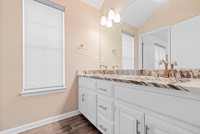 bathroom with hardwood / wood-style floors, vaulted ceiling, and double sink vanity