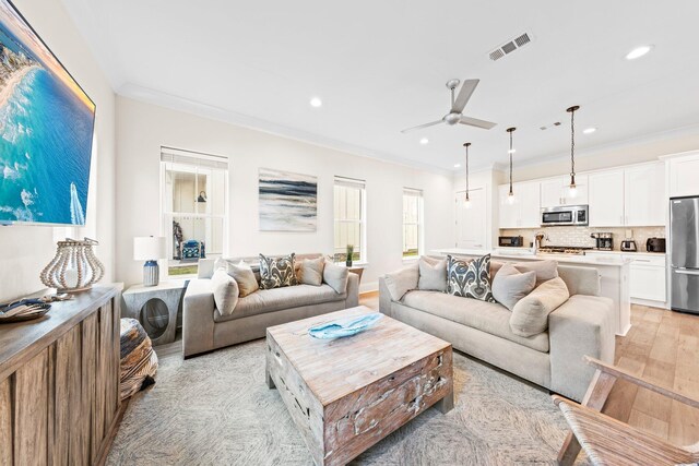 living room featuring crown molding, light wood-type flooring, and ceiling fan