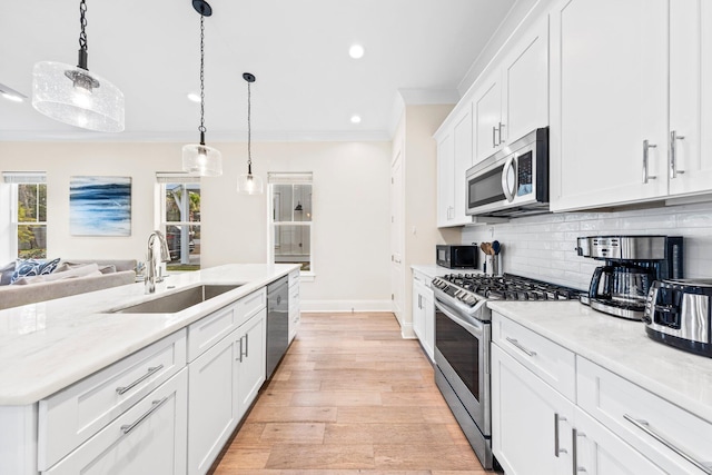 kitchen with ornamental molding, decorative backsplash, light wood-type flooring, and stainless steel appliances