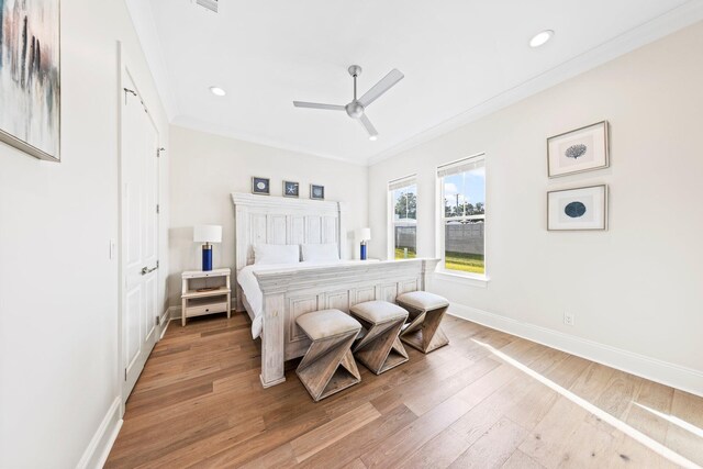 bedroom featuring ornamental molding, light wood-type flooring, and ceiling fan