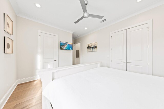 bedroom with ceiling fan, light hardwood / wood-style flooring, ornamental molding, and a closet