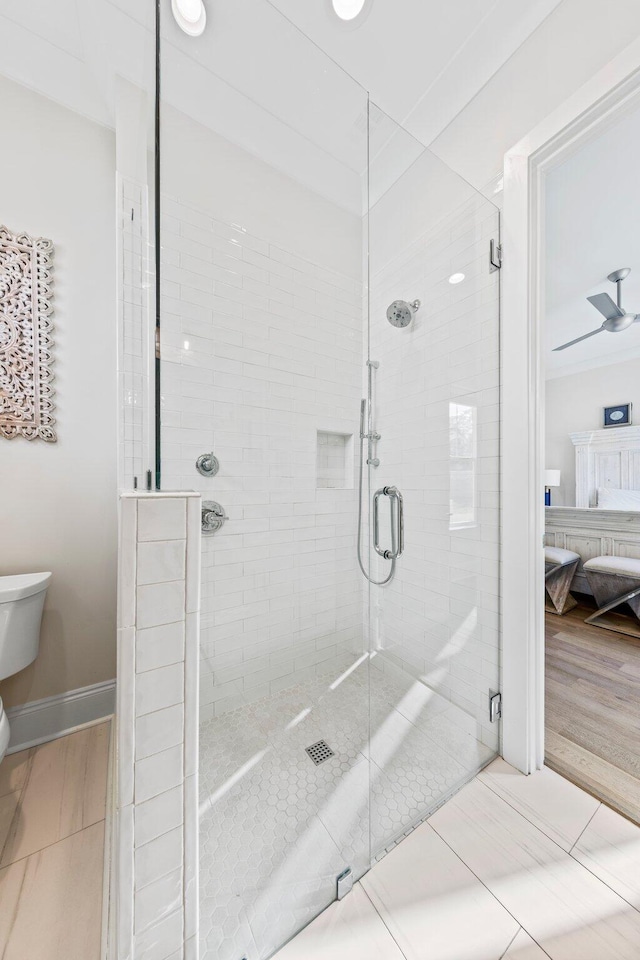 bathroom with toilet, hardwood / wood-style flooring, an enclosed shower, and ceiling fan