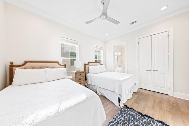 bedroom featuring crown molding, ceiling fan, light hardwood / wood-style floors, a closet, and ensuite bath