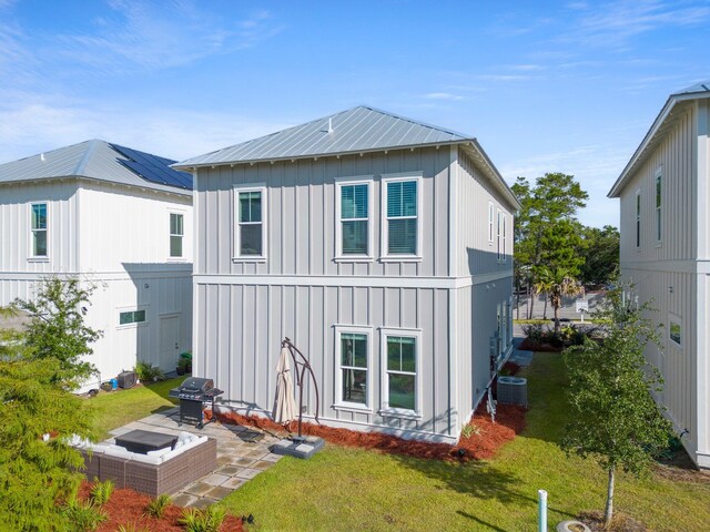 rear view of property featuring solar panels, a patio area, central AC, and a lawn