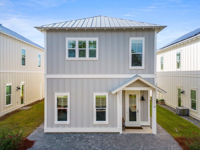 view of front of property featuring a patio, cooling unit, and a front yard