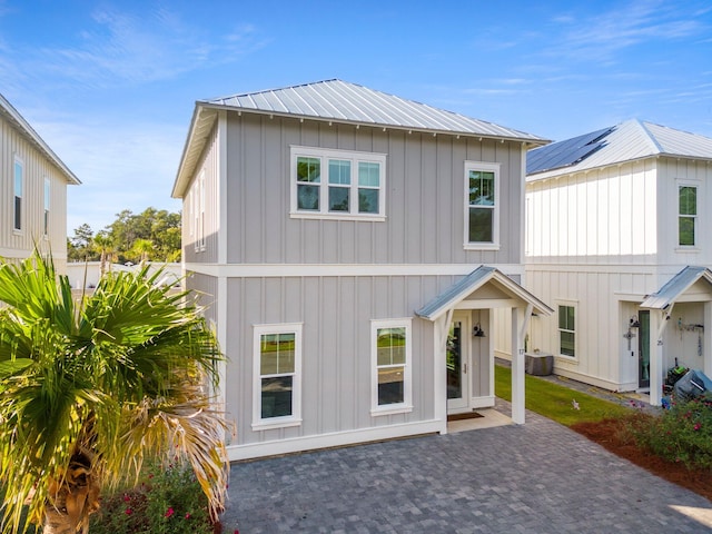 view of front of home featuring a patio, central air condition unit, and solar panels