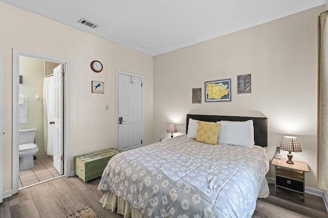 bedroom featuring hardwood / wood-style flooring and ensuite bathroom