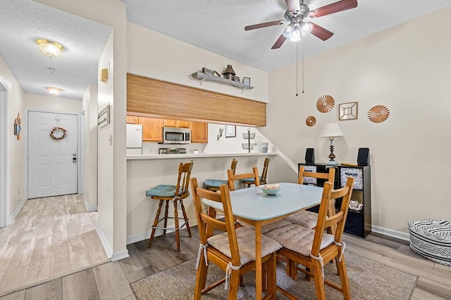 dining space with ceiling fan, light hardwood / wood-style floors, and a textured ceiling