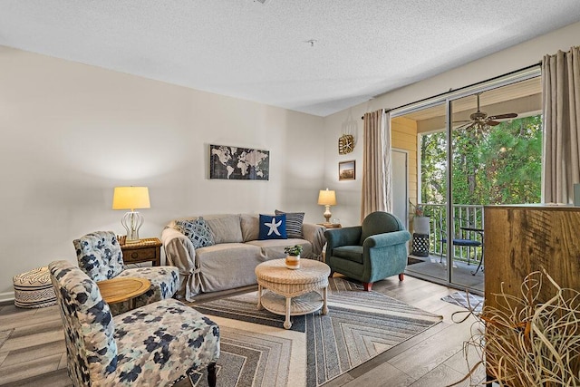 living room with ceiling fan, hardwood / wood-style flooring, and a textured ceiling