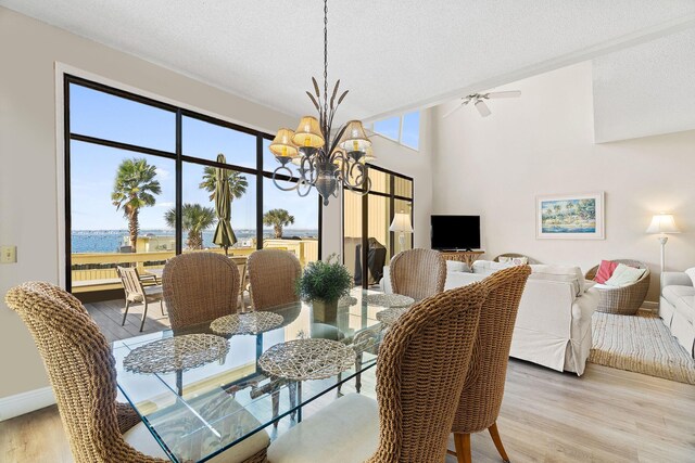 dining space featuring a water view, a notable chandelier, light hardwood / wood-style flooring, and a textured ceiling