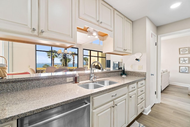 kitchen featuring white cabinetry, sink, stainless steel dishwasher, and light hardwood / wood-style flooring