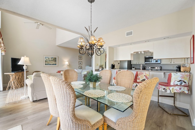 dining room featuring ceiling fan with notable chandelier, light wood-type flooring, and track lighting