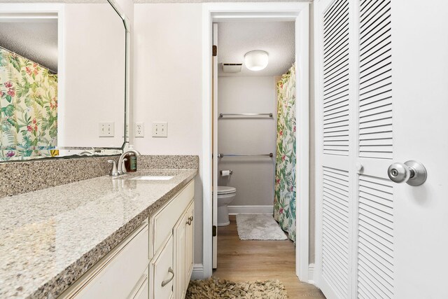 bathroom with vanity, a textured ceiling, toilet, and hardwood / wood-style floors