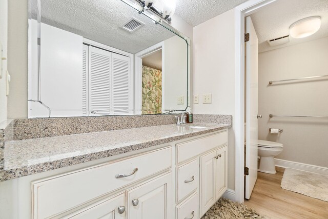 bathroom featuring vanity, a textured ceiling, wood-type flooring, and toilet