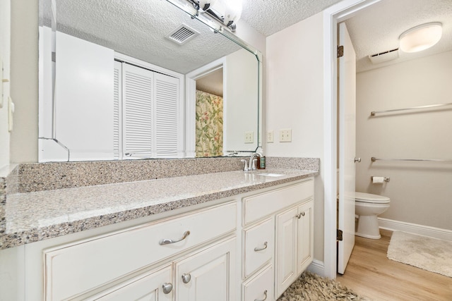 bathroom featuring vanity, hardwood / wood-style flooring, toilet, and a textured ceiling