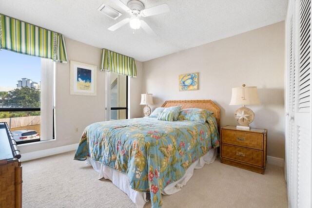 bedroom featuring a textured ceiling, light colored carpet, and ceiling fan