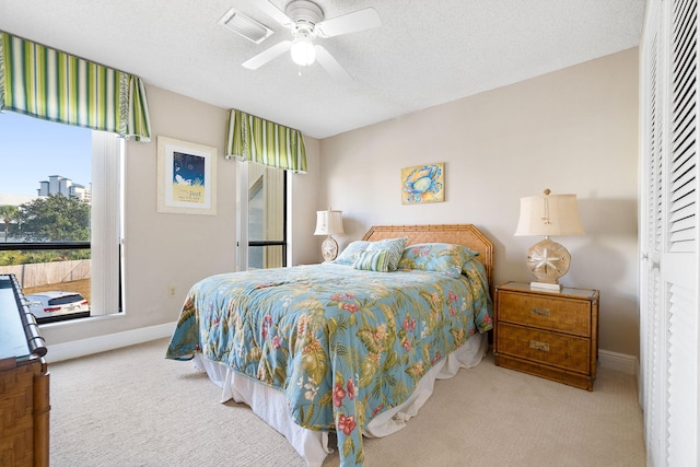 carpeted bedroom with ceiling fan and a textured ceiling