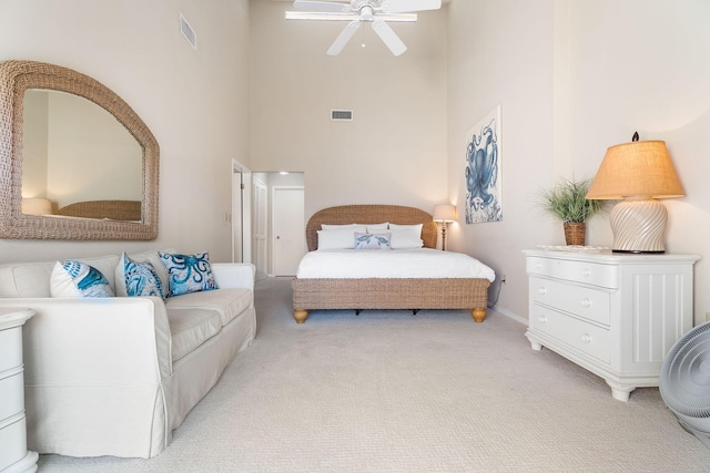 bedroom featuring ceiling fan, light colored carpet, and a high ceiling