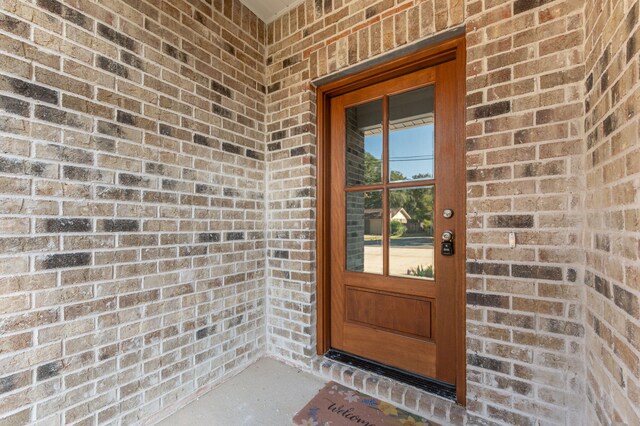 view of exterior entry featuring brick siding