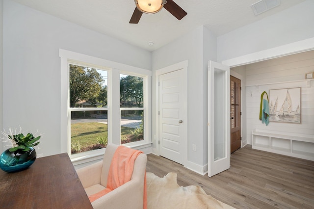 interior space with a ceiling fan, wood finished floors, visible vents, and a healthy amount of sunlight