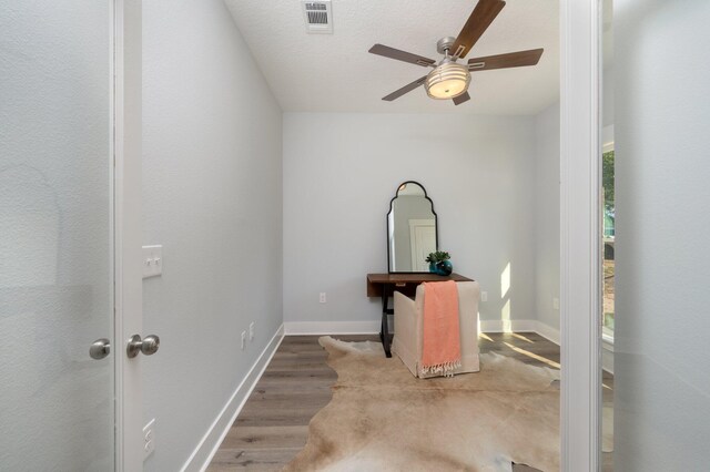 interior space with visible vents, a ceiling fan, a textured ceiling, wood finished floors, and baseboards