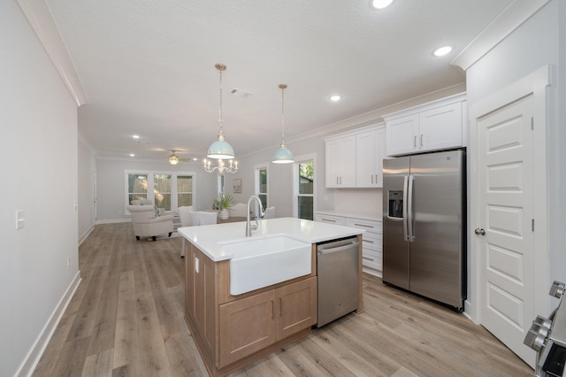 kitchen featuring stainless steel appliances, open floor plan, crown molding, and a sink