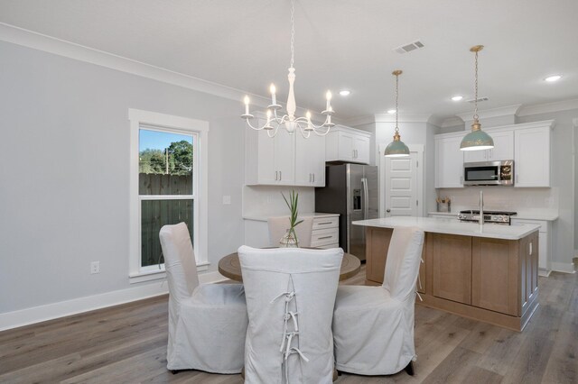 dining room featuring ornamental molding, visible vents, light wood-style flooring, and baseboards