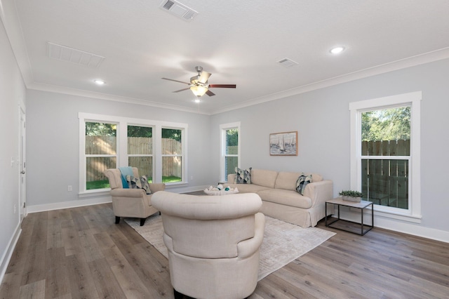 living area featuring crown molding, visible vents, plenty of natural light, and wood finished floors