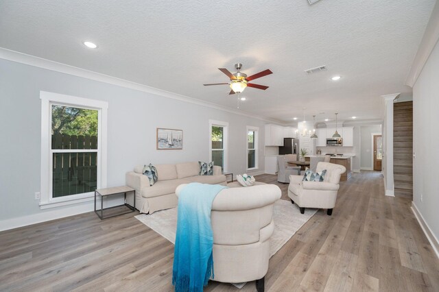 living area with light wood finished floors, visible vents, stairway, ornamental molding, and a textured ceiling