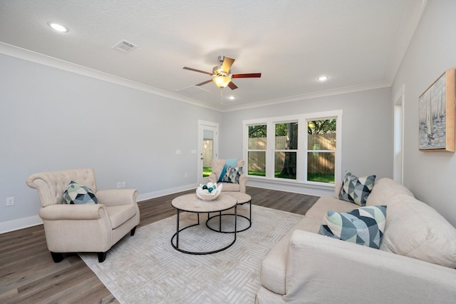 living room featuring visible vents, crown molding, baseboards, and wood finished floors