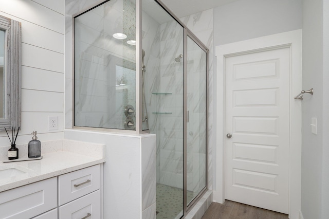 full bath featuring vanity, a marble finish shower, and wood finished floors