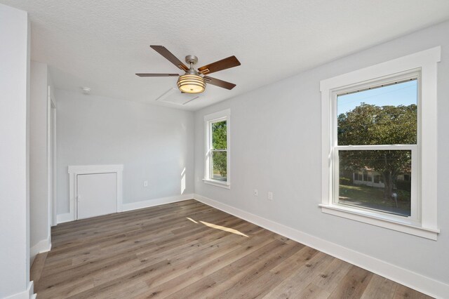 empty room featuring a ceiling fan, a textured ceiling, baseboards, and wood finished floors