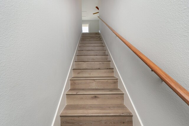 stairway featuring a textured wall and wood finished floors