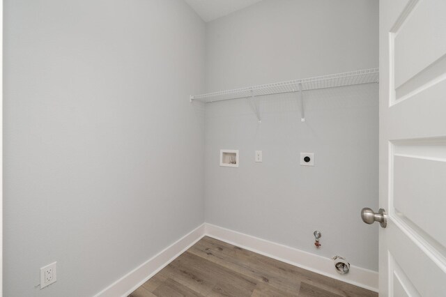 clothes washing area with washer hookup, electric dryer hookup, wood finished floors, laundry area, and baseboards