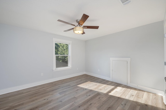 unfurnished room with a ceiling fan, wood finished floors, visible vents, and baseboards