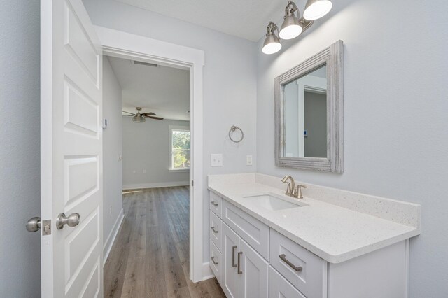 bathroom with ceiling fan, wood finished floors, visible vents, vanity, and baseboards