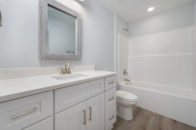 full bathroom with bathing tub / shower combination, recessed lighting, toilet, vanity, and wood finished floors