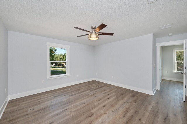 unfurnished room with a textured ceiling, baseboards, and wood finished floors